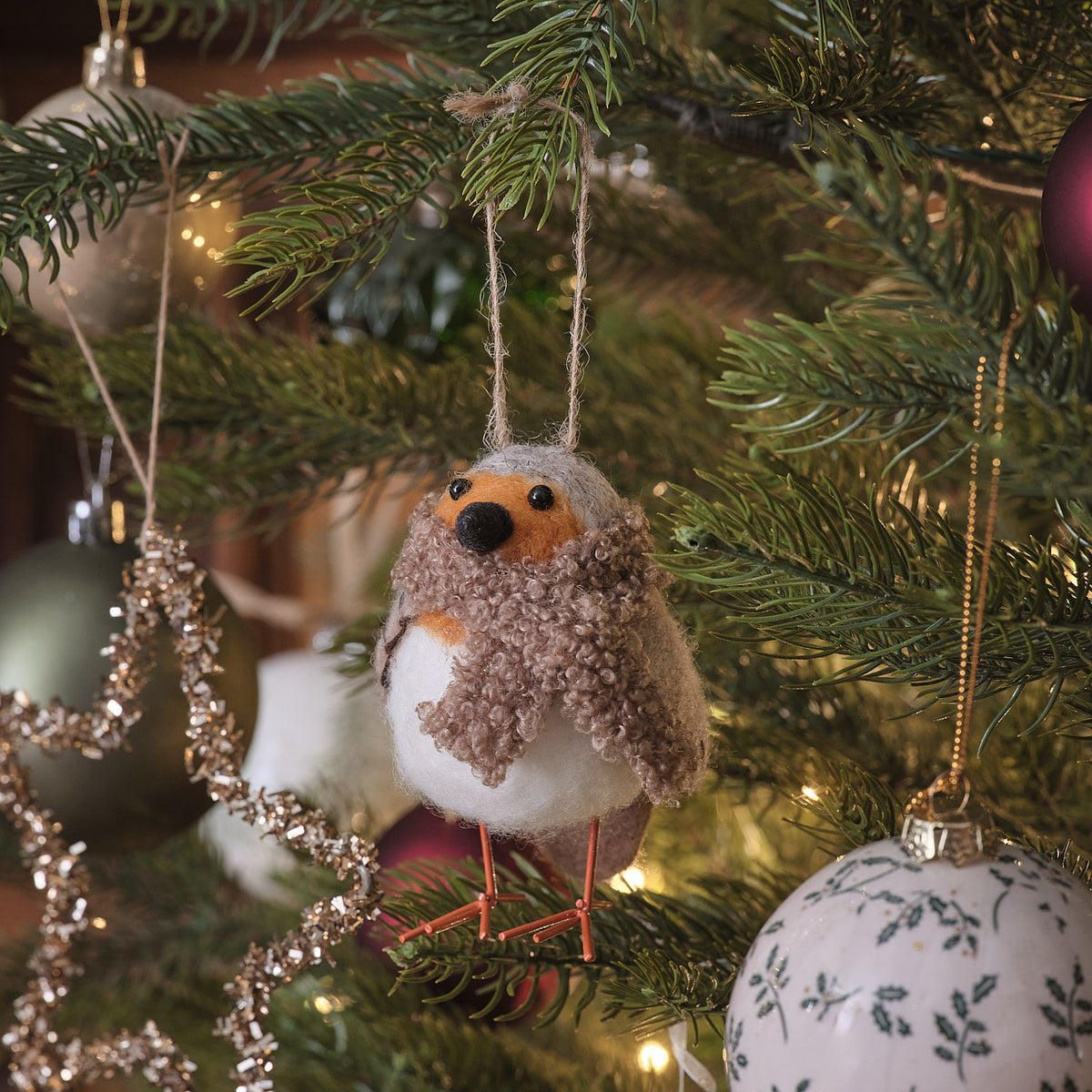 Zwei rosa-cremefarbene Vogel-Dekofiguren mit roten Weihnachtsmützen, positioniert im verschneiten Außenbereich vor grünem Fichtengrün und natürlichem Gartenhintergrund – robuste Weihnachtsfiguren für Außendekoration, Balkon-Arrangements und winterliche Gartenszenen mit festlichem Appeal.