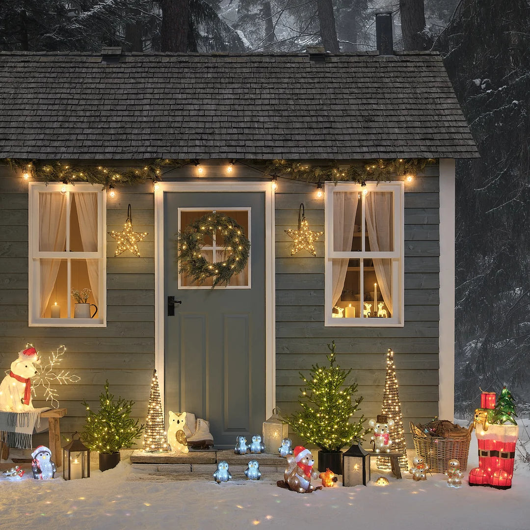 Festliche Weihnachtsszene mit glitzernder Maus-Dekofigur, illuminiertem Weihnachtshaus mit warmweißer LED-Beleuchtung, roten Weihnachtsdekoelementen und grünen Grünflächen-Akzenten – umfassendes Außen-Weihnachtsdisplay mit charmanter Teddybär-Figur für gehobene Garten- und Hausdekorationen.