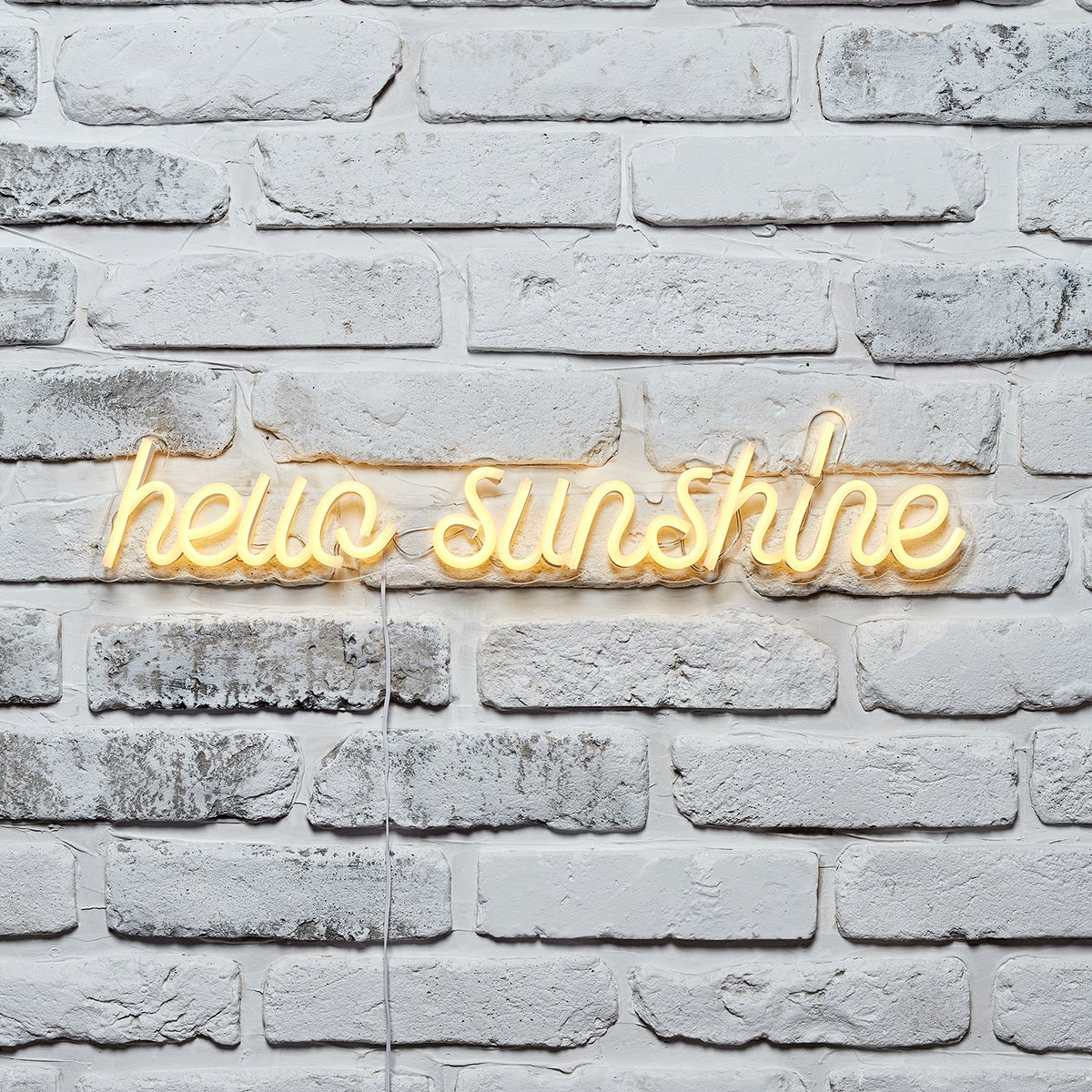 hello sunshine gelbe Neonschrift an weißer Ziegelwand.